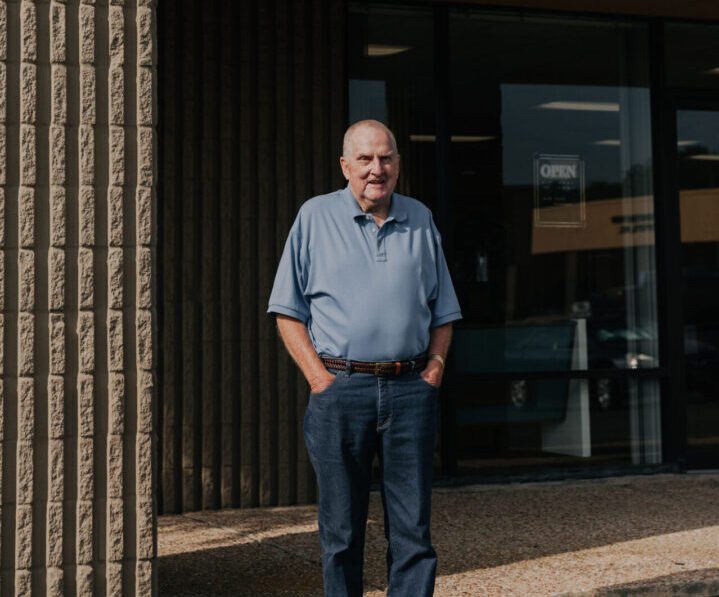 A man standing in front of a building with his hands in his pockets.